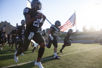 SC Football running with flag at Homecoming